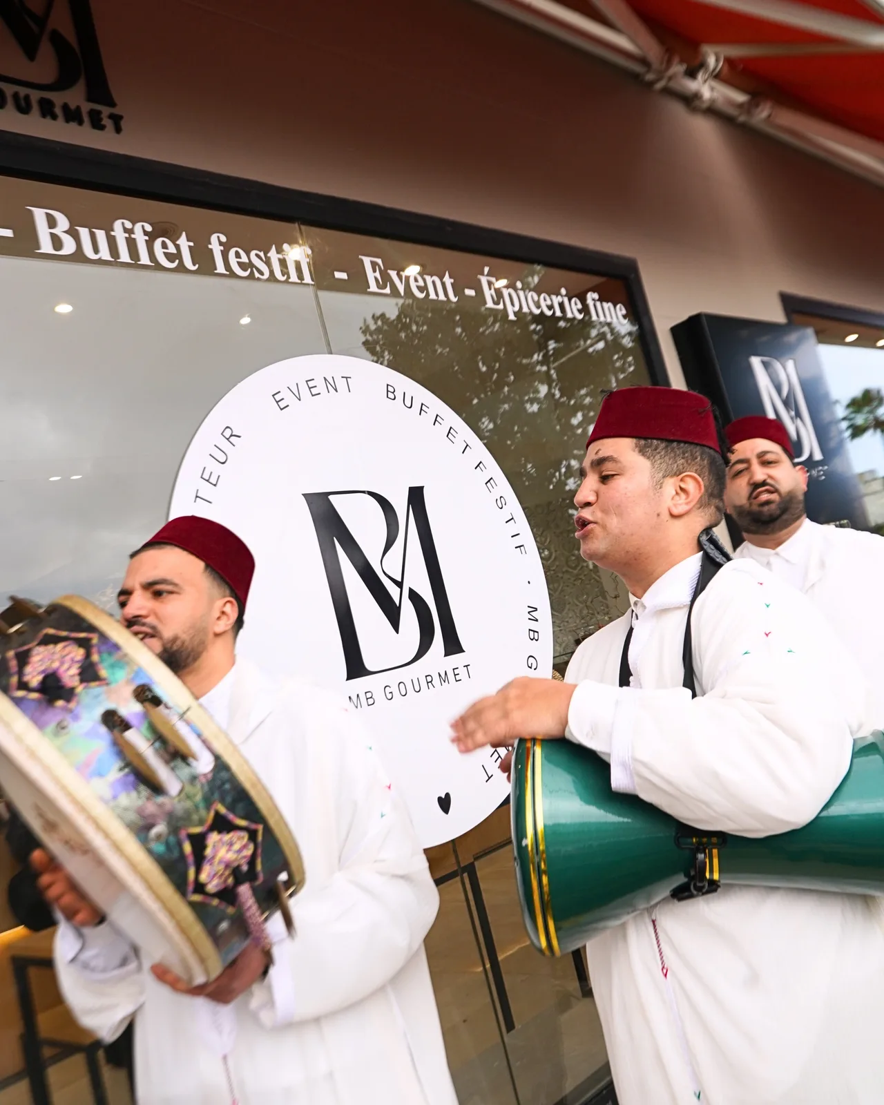 Musiciens accueil traditionnel devant logo MB Gourmet